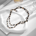 Minimalist double-layer gold chain necklace with black crystal beads on white tray - Necklace