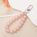 Cinturino per telefono con perline rosa e chiusura argento su sfondo beige - Rosa