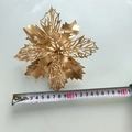 Vue de dessus d'une fleur de poinsettia dorée mesurée à 15 cm avec un ruban à mesurer - Fleur de Noël Dorée
