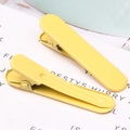 Close-up of two yellow metal duckbill hair clips with a smooth matte lacquer finish - 1.3x4.9cm / Yellow