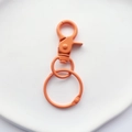 Close-up of bright orange painted metal lobster clasp hook and ring for bags and DIY crafts - Orange