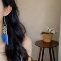 Boucles d'oreilles bohèmes à plumes bleues portées par un mannequin dans un cadre doux - Gland de Plume Bohémien Long (15#)
