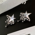 Detalle macro de pendientes de estrella con nácar incrustado y borlas de circón fino - Meteorito Plateado (Nácar)