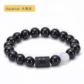 Close-up of black onyx beaded bracelet featuring an engraved Aquarius zodiac stone charm - Aquarius