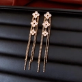 Détail de boucles d'oreilles fleuries dorées 18K avec franges et incrustation blanche - Doré