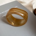 Close-up of a vintage amber resin wide ring with unique textures on a grey book - 23# Wide Band Amber Ring Style (Size 23 Bangle - Brown)