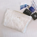 Dettaglio della borsa trucco bianca con fiori a rilievo e cosmetici di lusso - Bianco