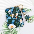 Detail of floral PU leather card holder with tassel pendant and gold metal keychain - Black Floral