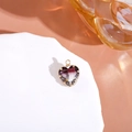 Golden heart pendant with purple-grey gradient crystal on a white textured display - Black+White