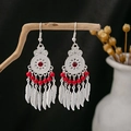 Detail of bohemian silver earrings with red beads and feather tassels on wood branch - Feather Tassel Red Beads Silver Style (E4627-1/Red)