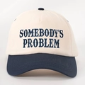 Dettaglio del ricamo Somebodys Problem su cappellino bicolore beige e blu navy - Crema/Blu Navy