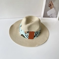 Detailansicht eines beigen Strohhuts mit blauem Blumenband und Leder-Patch-Akzenten - Beige