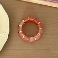 Détail de perles en résine ambrée et séparateurs dorés sur une surface en bois rustique - Rouge pastèque