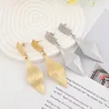 Detailed view of geometric textured gold and silver drop earrings on a stylish tray - Gold EH008 (Textured Rhombus)