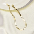 Detail van gouden platte slangenketting met karabijnsluiting en K18 kenmerk - Armband / Goud