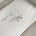 Macro shot of silver bow pendant and sleek snake chain on a minimalist white card - Bow / Silver