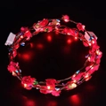 Detail showing the red LED rose headband with glowing lights and battery box on black background - Red