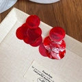 Detalle de pendientes de nácar rojo con lentejuelas sobre un libro y una mesa de madera - Poste de pendiente de plata - Rojo