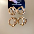 Dettaglio macro di grandi orecchini a pendente sferici intrecciati in metallo dorato - Oro