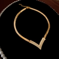 Primo piano di una collana a V placcata oro con micro cristalli su velluto nero - Collana a V dorata con strass