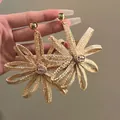 Macro-opname van handgeweven zonnebloem oorbellen met natuurlijke vezels en gouden knopjes - Zonnebloem Geweven Stijl / Bruin / Zilveren naald