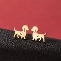 Detalle de pendientes de perro salchicha dorados en un soporte de cuero texturizado - Dorado