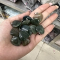 Green and brown heart-shaped stone pendants with metal clips held in hand - India Agate