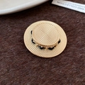 Dettaglio ravvicinato della spilla a cappello di paglia dorata con cordino intrecciato - Oro