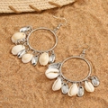 Natural seashell and silver metal hoop earrings on a sandy beach with a straw hat - Silver