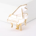 Detalle de broche de piano de esmalte blanco con toques dorados sobre un pedestal limpio - Blanco