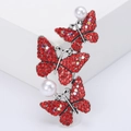 Vue macro d'une broche papillon argentée avec strass rouges et perles blanches - Rouge