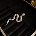 Dettaglio macro di una spilla a serpente placcata oro 14k con pavé di zirconi e occhi neri - Oro (Placcato Oro Vero)