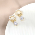 Dettaglio orecchini a fiocco con perle e zircone a goccia su un piatto bianco elegante - Oro