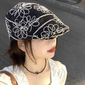 Retro black beret hat with detailed white floral embroidery worn by female model - Embroidered Flowers - Black
