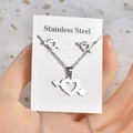 Dettaglio del set collana e orecchini in acciaio con ciondoli a cuore trafitto e freccia - TT-169 Freccia Attraverso il Cuore