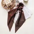 Detail of metallic pleated hair scrunchie with long ribbons in bronze finish - Glossy Coffee Streamer