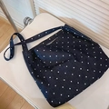 Detail view of a large denim tote bag featuring white polka dots on a white chair - Polka Dot