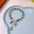 Ethnic silver bracelet with blue crystal beads and festive good luck charms on a white tray - Grey Blue Crystal Peanut Abacus Fortune Cat Bracelet