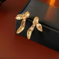 Close-up of golden streamlined petal earrings with brushed texture on a black jewelry box - Gold