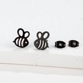 Detailed close-up of minimalist black bee stud earrings on a textured white surface - 276 Black (Bee)