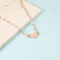 Detalle del collar de corazón en oro rosa con cadena de clip sobre base de piedra - Oro rosa