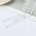 Close-up of transparent plastic U-shaped hair pins for bun styling on white textured fabric - Clear