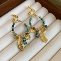 Dettaglio di orecchini a piuma dorati boho con perline turchesi in una scatola portagioie - Stile Clip per Orecchi a Vite (Per Orecchie Senza Buchi) / Placcato in Oro Vero Oro-Verde Scuro