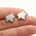 Macro detail of silver maple leaf stud earrings made of polished stainless steel on finger - Maple Leaf / Steel
