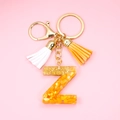 Detail of yellow resin letter Z keychain with gold flakes and colorful tassels - Letter Z
