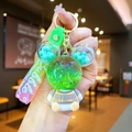Close-up of green cartoon bear keychain with liquid glitter and colorful silicone strap - Green Sitting Bear with Gradient Rope