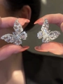 Gros plan de boucles d'oreilles papillon en argent avec zircons brillants en main - Style Pavé de Strass Papillon (29#)