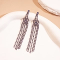 Vue détaillée des boucles d'oreilles à pompons violets avec strass sur un plateau - Coeur Creux / Violet