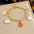 Detailed shot of a gold charm bracelet with enamel ladybug, bee, and daisy pendants - Multi-Charm Bracelet (B1738)