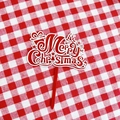 Macro shot of red acrylic Merry Christmas cake topper on red white plaid cloth - Christmas Tree Gift Double Layer Merry Christmas